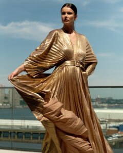 Model on an NYC rooftop, spinning with a ruffled gold dress